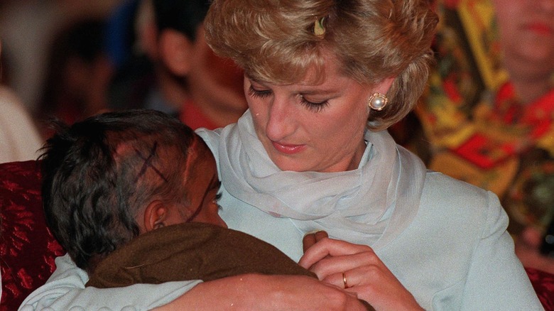 Diana, Princess of Wales, cradling a young Cancer patient in her arms