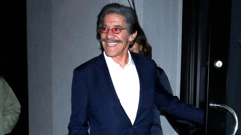 Geraldo Rivera grins while exiting a building.