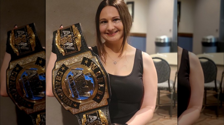 Gypsy Rose Blanchard smiling holding a wrestling belt