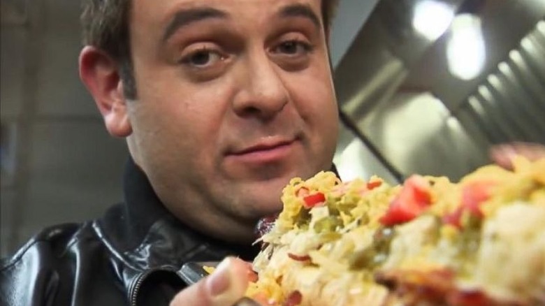 Adam Richman holding up food