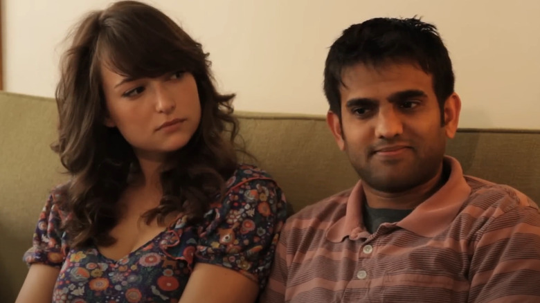 Milana Vayntrub and Sandeep Parikh sitting on a sofa