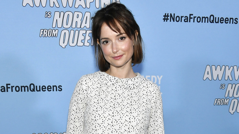 Milana Vayntrub wearing white dress at "Awkwafina is Nora From Queens" Premiere