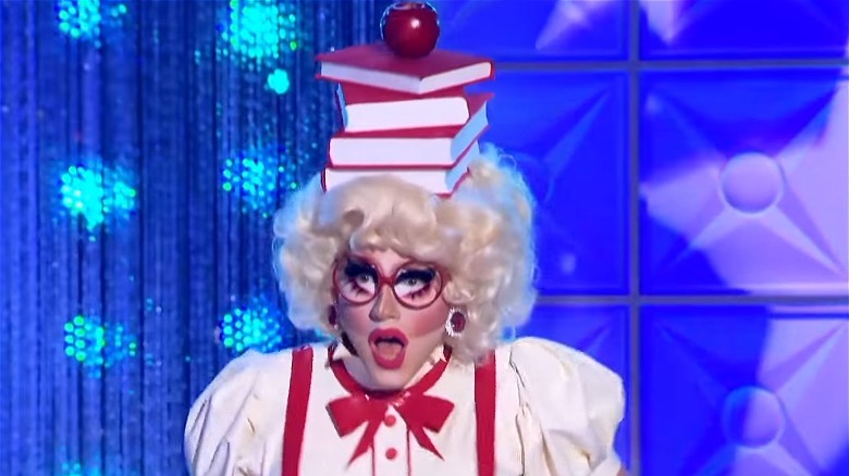 Trixie Mattel stack of books on head with apple