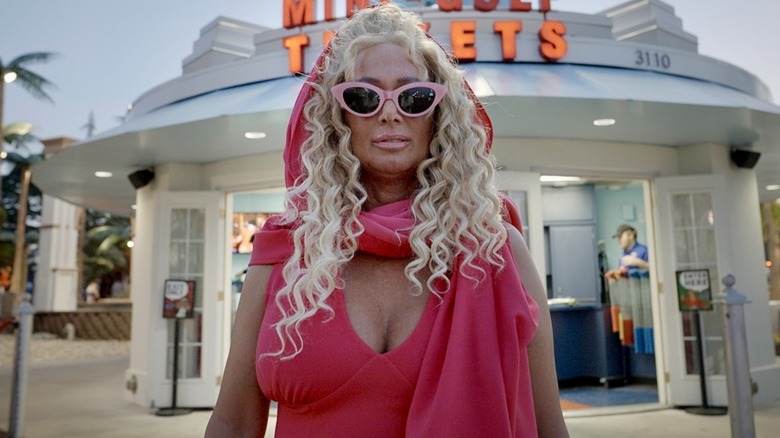 Tonia Haddix posing in front of a restaurant in pink cat-eye sunglasses