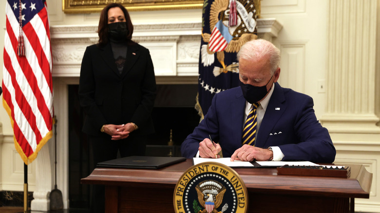 Kamala Harris watching Joe Biden sign paperwork 