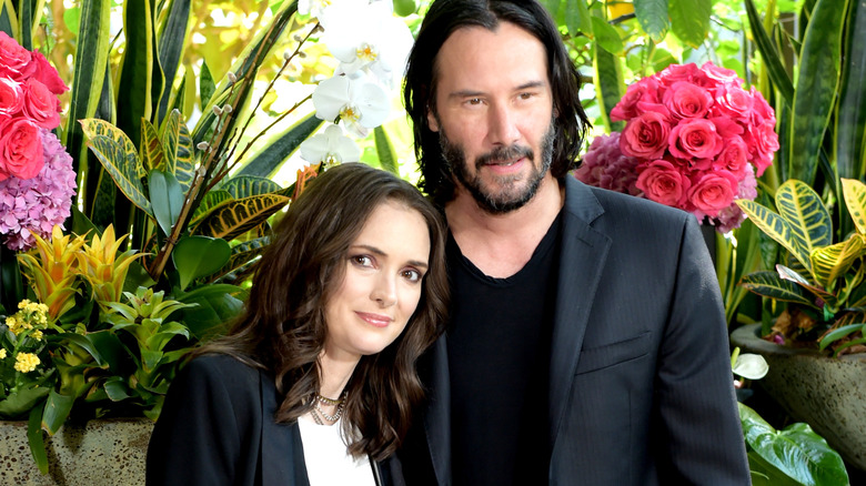 Winona Ryder and Keanu Reeves posing with flowers