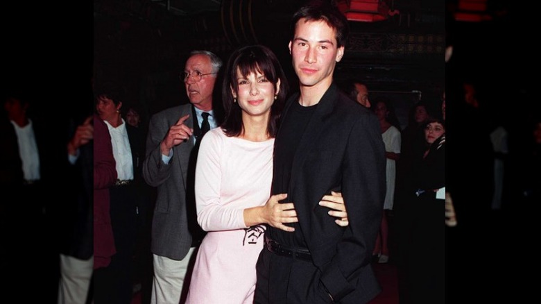 Sandra Bullock with her arms around Keanu Reeves