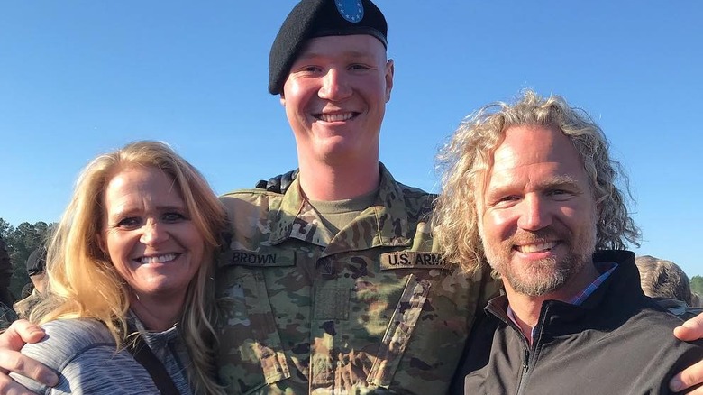 Paedon Brown with arms around parents