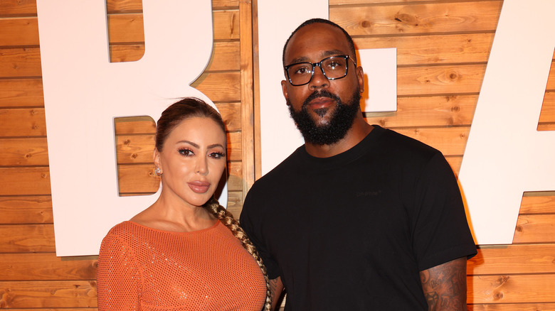 Larsa Pippen in orange dress; Marcus Jordan wearing black shirt