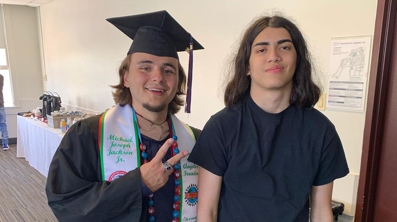 Prince Jackson wearing a black cap, gown, and stoll with Bigi Jackson wearing a black t-shirt