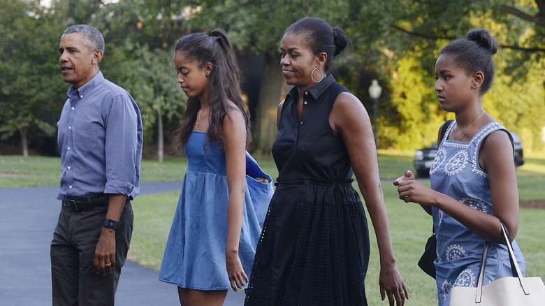 Sasha and Malia walking with Michelle and Barack Obama