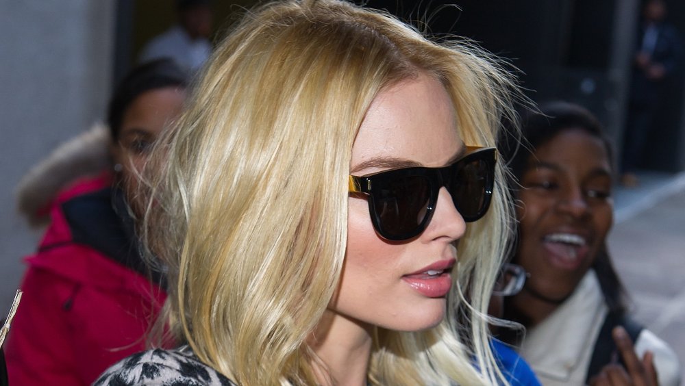 Margot Robbie outside, wearing sunglasses, with a neutral expression