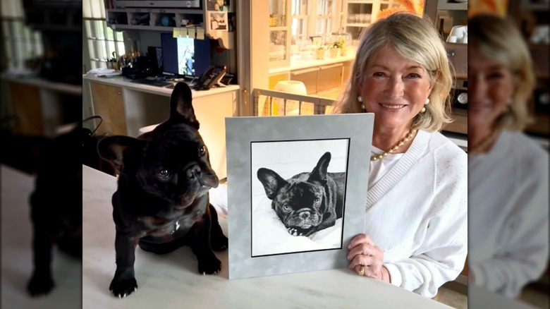 Martha Stewart poses alongside her dog Luna Moona holding an artwork of the dog.