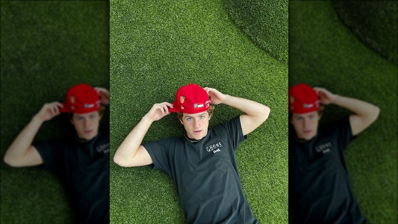 MattyBRaps lying on grass with a baseball cap in 2022