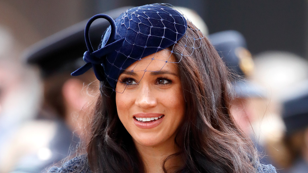 Meghan Markle, the Duchess of Sussex, smiling and wearing navy blue