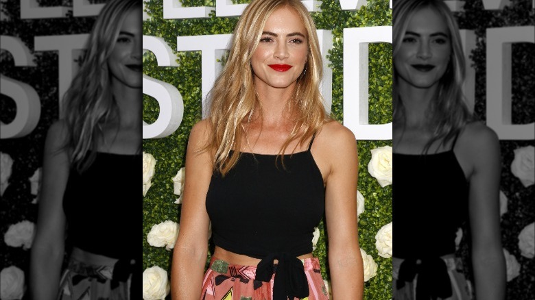 Emily Wickersham posing in front of backdrop at an event