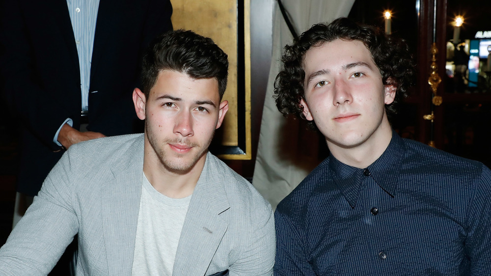 Nick and Frankie Jonas seated at a table 