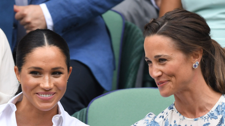 Pippa Middleton and Meghan Markle smiling and talking