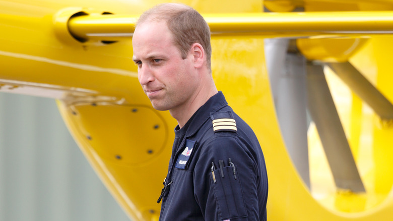 Prince William standing next to helicopter