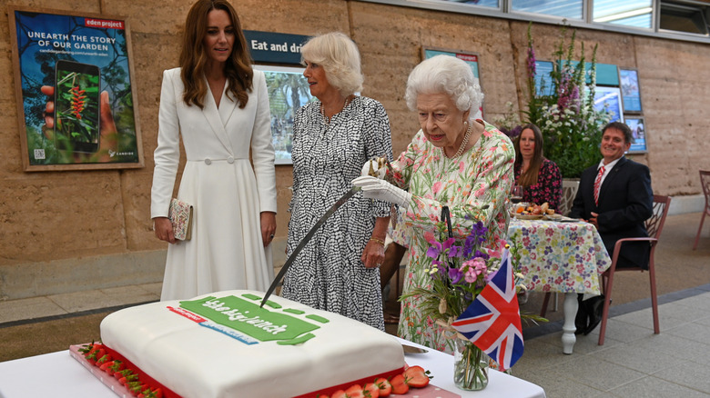 Queen Elizabeth II cutting cake with a ceremonial sword