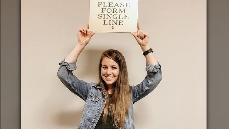 Jana Duggar holding 'please form single line' sign