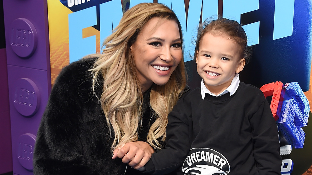 Naya Rivera crouching down and smiling holding the hand of her son, Josie Hollis Dorsey