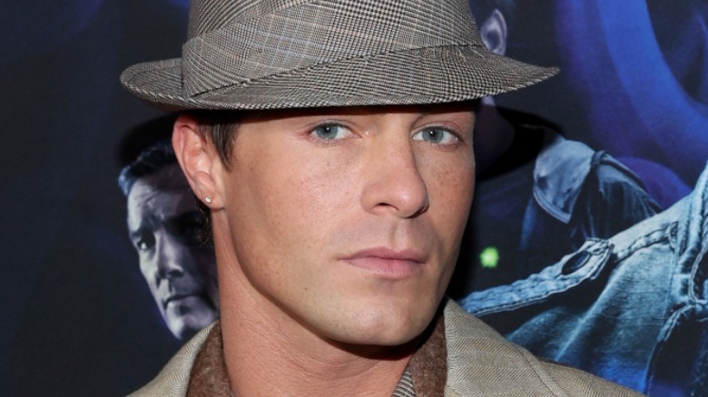 Colton Haynes wearing a hat on the Teen Wolf red carpet, looking at camera