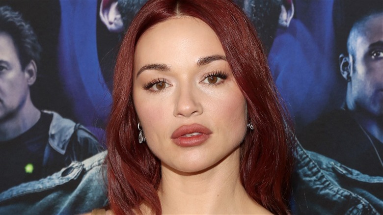 Crystal Reed red hair blue background, looking at camera