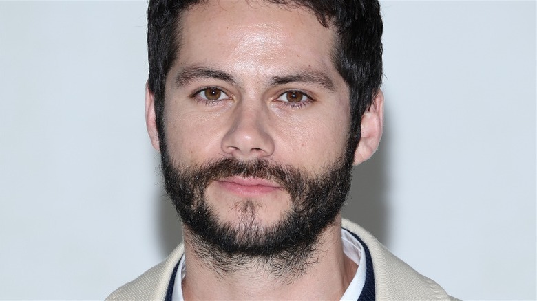 Dylan O'Brien white wall scruffy beard, looking at camera