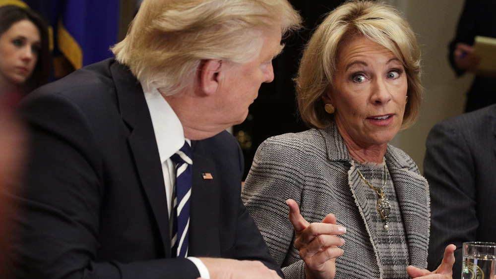 President Trump looking over at a finger-pointing Betsy DeVos