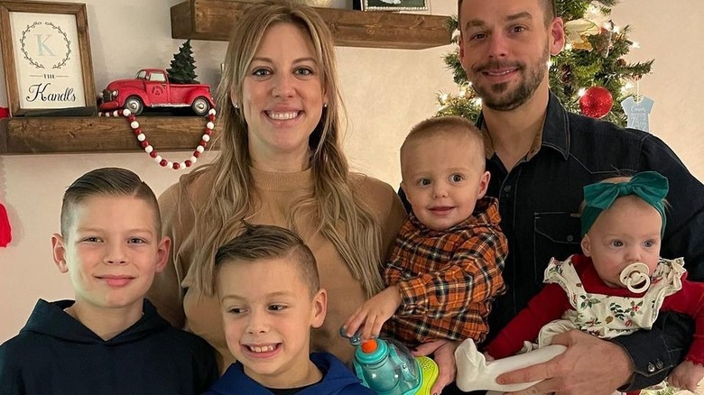 Briana and Ryan Culberson posing in front of the Christmas tree with their four children