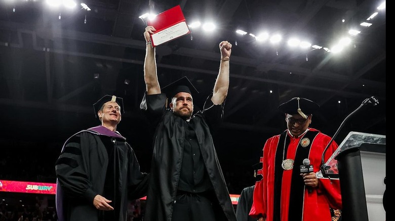 Travis Kelce holding up his diploma at graduation ceremony 