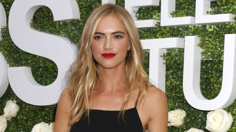 Emily Wickersham with red lipstick in front of floral backdrop