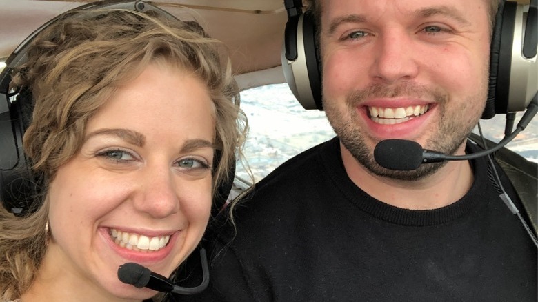 Abbie Burnett and John David Duggar smile while flying a plane