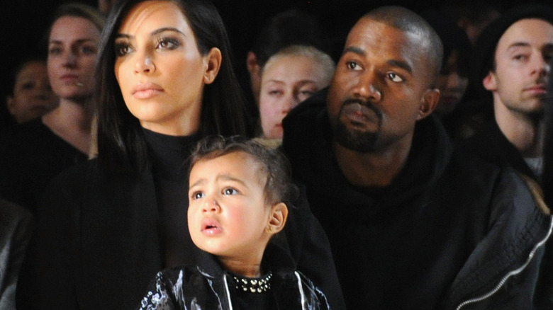 Kim Kardashian with Saint and Kanye West at a fashion show