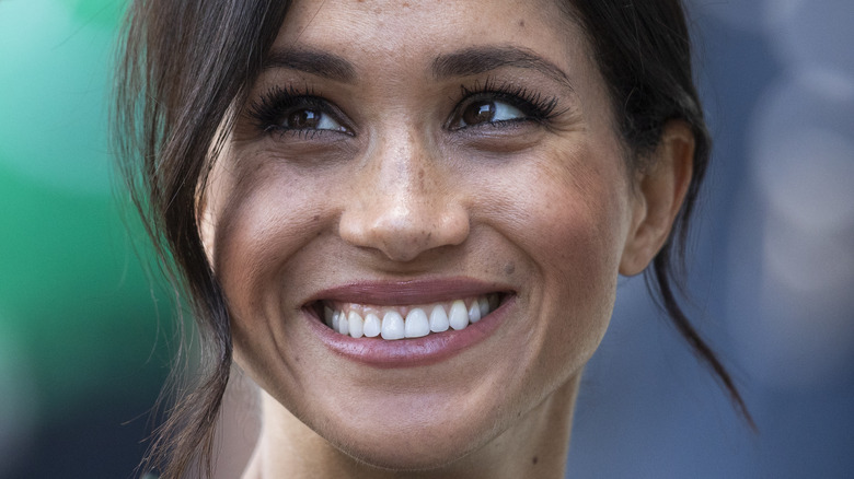 Meghan Markle smiles while looking up