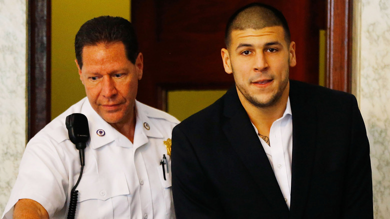 Aaron Hernandez handcuffed and being led by a police officer