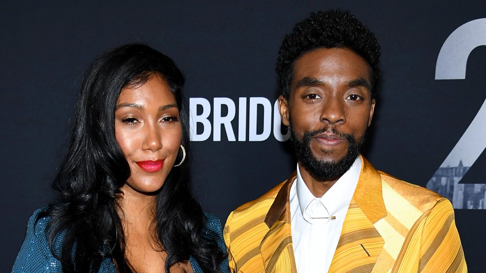 Taylor Simone Ledward in a blue dress, Chadwick Boseman in a yellow-patterned suit, posing together