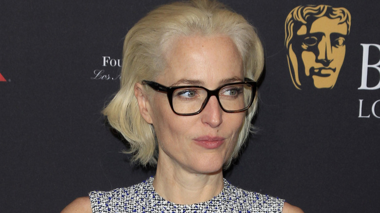 Gillian Anderson pursing her lips and wearing black glasses