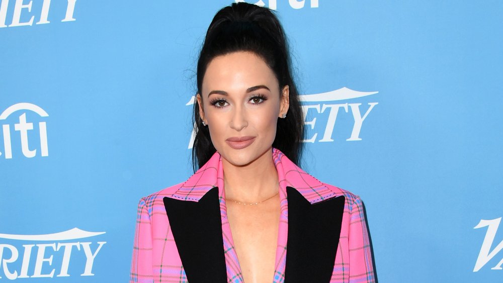 Kacey Musgraves with black ponytail and pink blazer