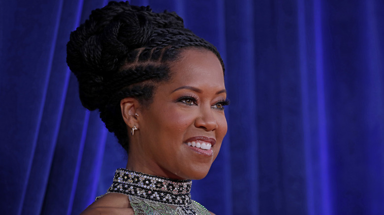 Regina King smiling in front of blue curtains