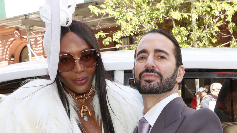 Naomi Campbell posing in white fascinator next to Marc Jacobs