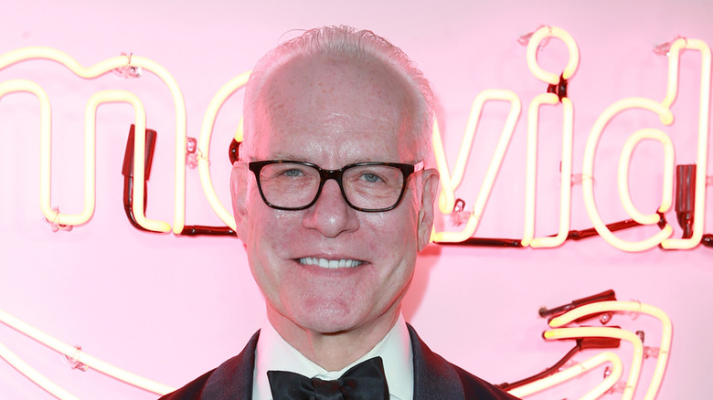 Tim Gunn smiling in front of pink backdrop