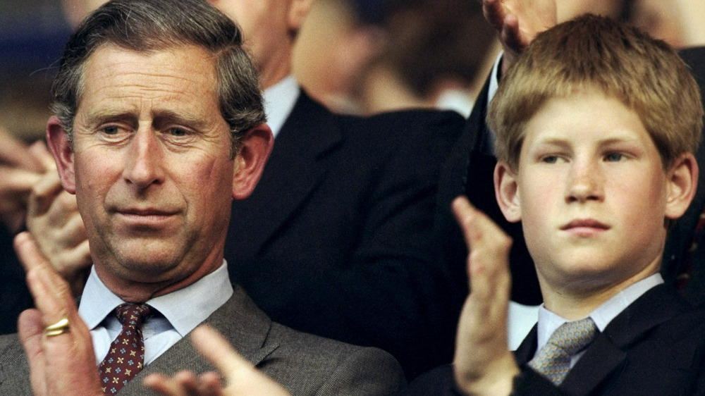 Prince Charles applauding next to a young Prince Harry