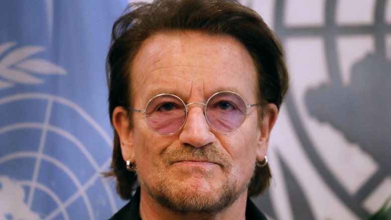 Bono posing in front of the United Nations flag