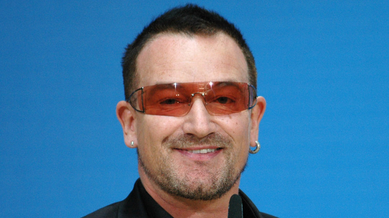 Bono wearing sunglasses in front of a mic