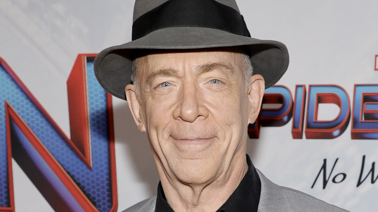 J. K. Simmons smiling in a gray hat