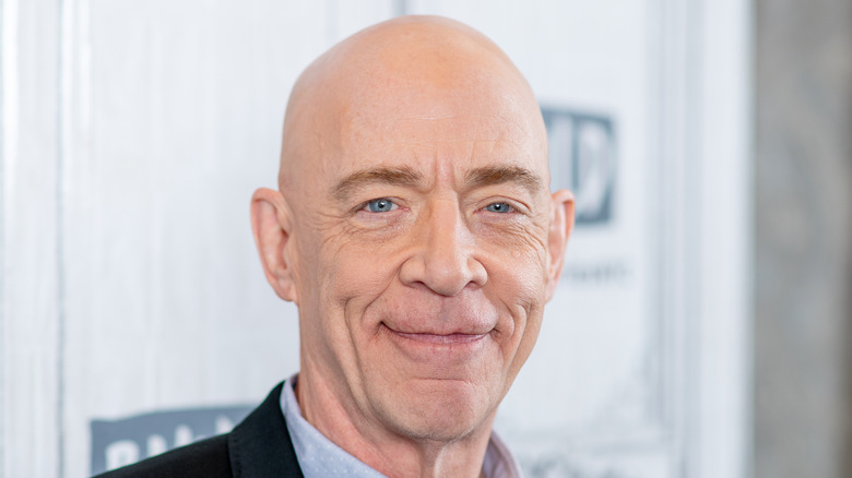 J. K. Simmons smiling with shaved head 