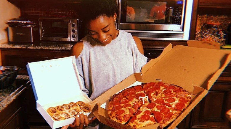 Simone Biles smiling at pizza