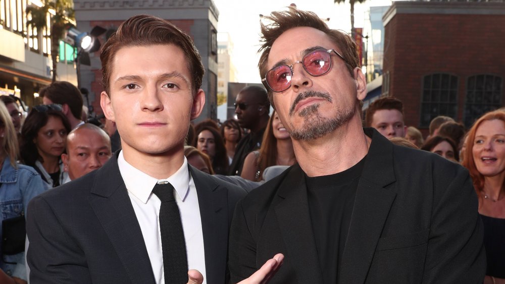 Tom Holland and Robert Downey Jr., posing at a movie premiere with serious expressions